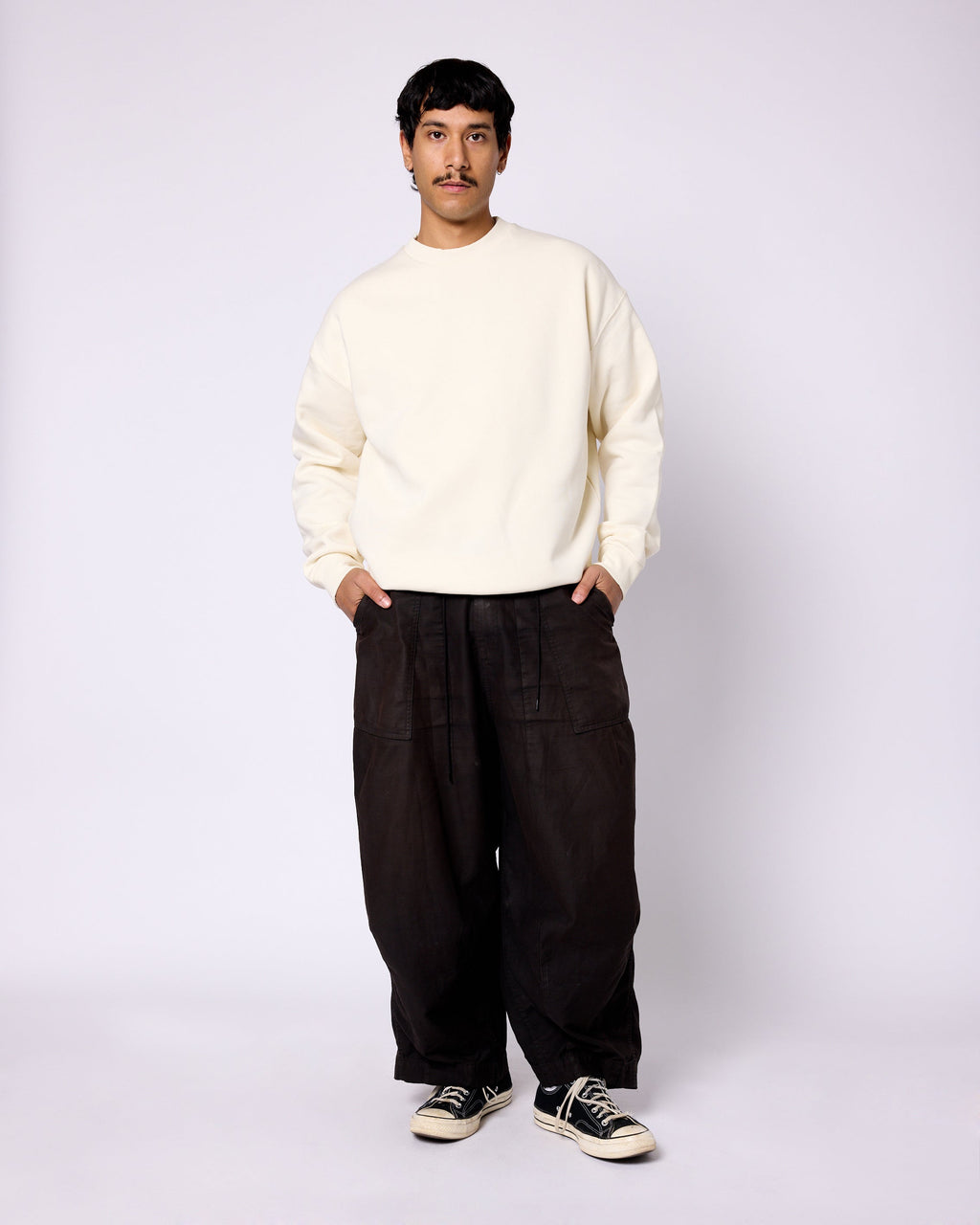 Model wearing an off-white, long-sleeve crewneck sweatshirt with a relaxed fit and dropped shoulders.