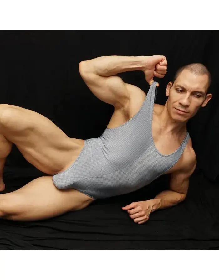 Grey thong tank top bodysuit made of stretchy material featuring a scoop neckline and slim straps modeled by a man by Arroyman