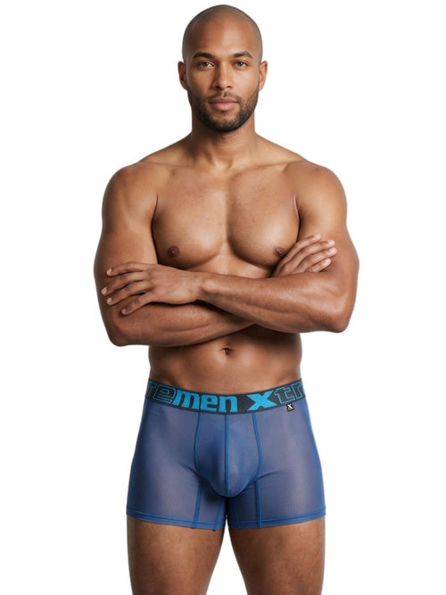 A man wearing blue mesh boxer briefs with a branded waistband, standing with arms crossed.
