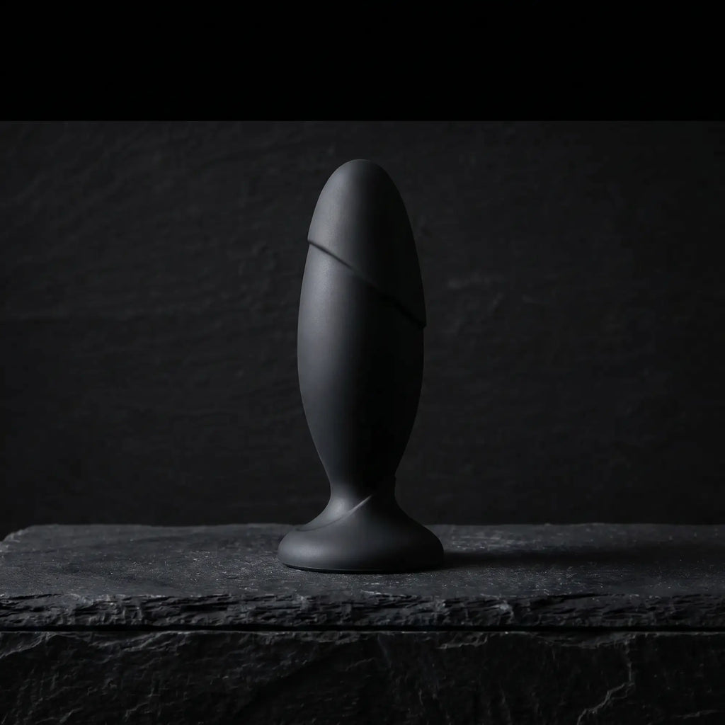 Anal Adventures Platinum Silicone Rocket Plug matte black on dark stone surface, cinematic luxury product photography