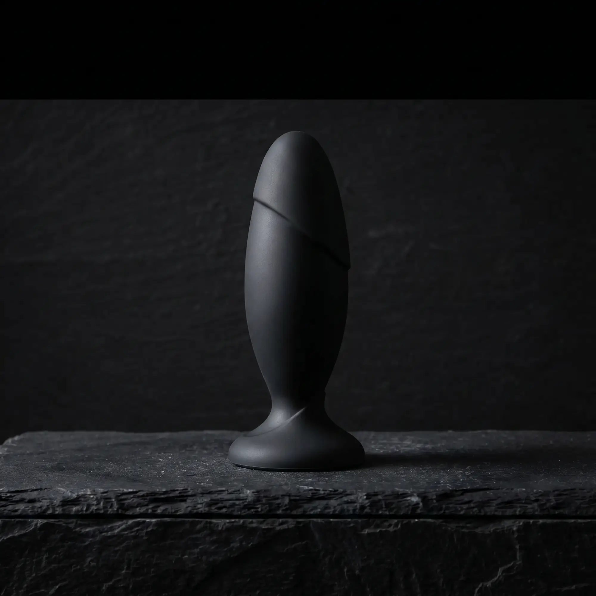 Anal Adventures Platinum Silicone Rocket Plug matte black on dark stone surface, cinematic luxury product photography