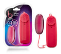 A vibrant red power bullet remote control with star-shaped button and matching cord beside a pink glossy device in packaging