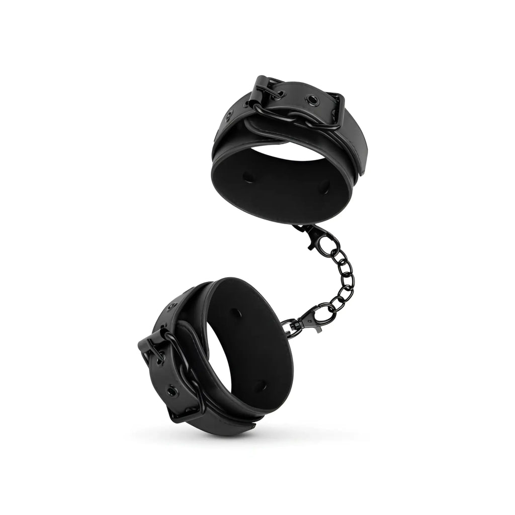 Bedroom Fantasies faux leather black wrist cuffs connected by a chain for intimate bondage play