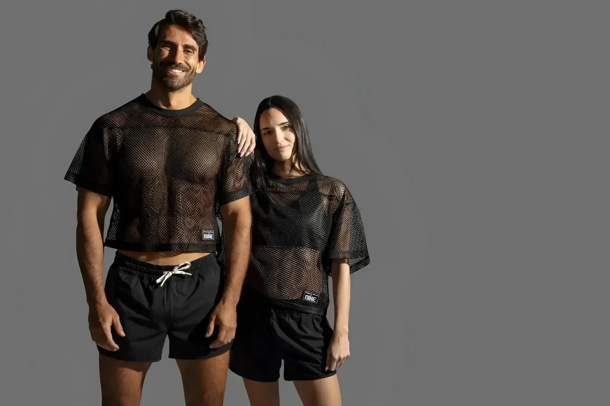 BIKE Athletic BAM134 short sleeve practice jersey in black. Lifestyle shot featuring a man and woman in black jerseys.