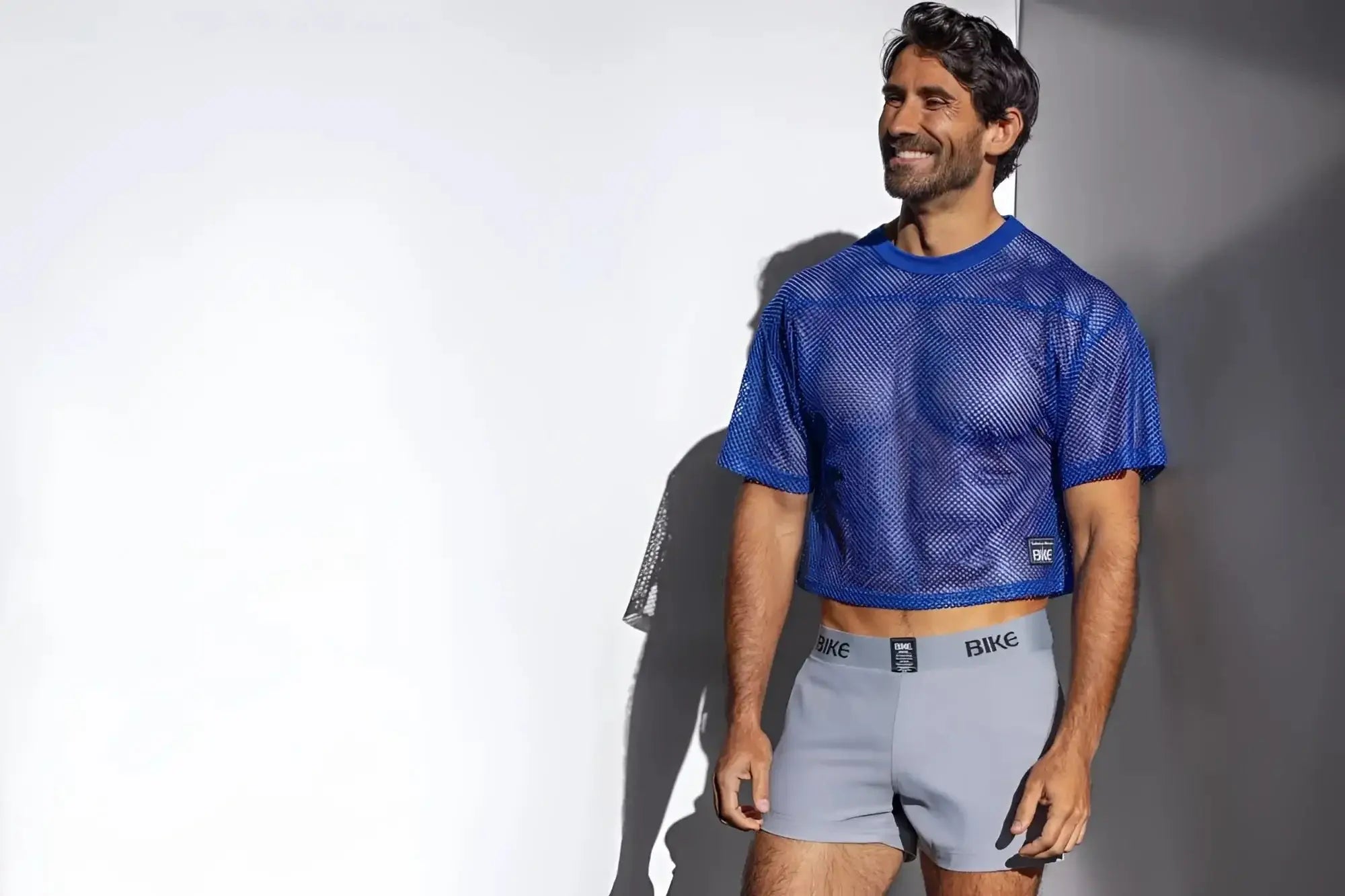 Man wearing a bright blue mesh crop top and light grey Bike brand boxer briefs.
