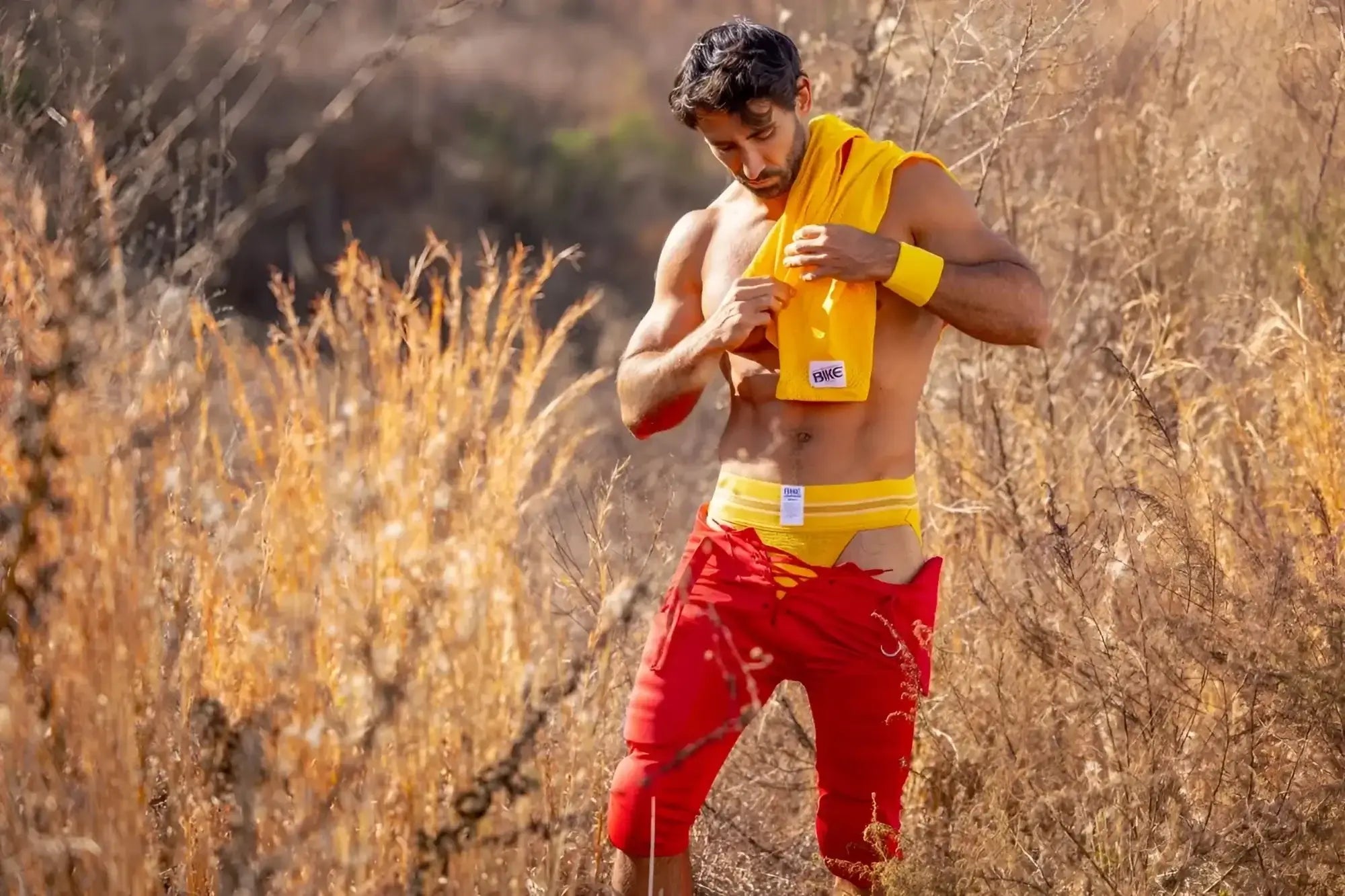 Lifestyle shot of a man wearing a yellow BIKE Athletic BAS306 Original Number 10 jockstrap outdoors.
