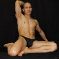 Model wearing black mesh bikini underwear by Arroyman showcasing a sleek fit and breathable material against a dark background.