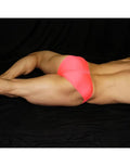 Neon pink men's bikini underwear by Arroyman featuring a snug fit and smooth fabric shown on a model lying down.