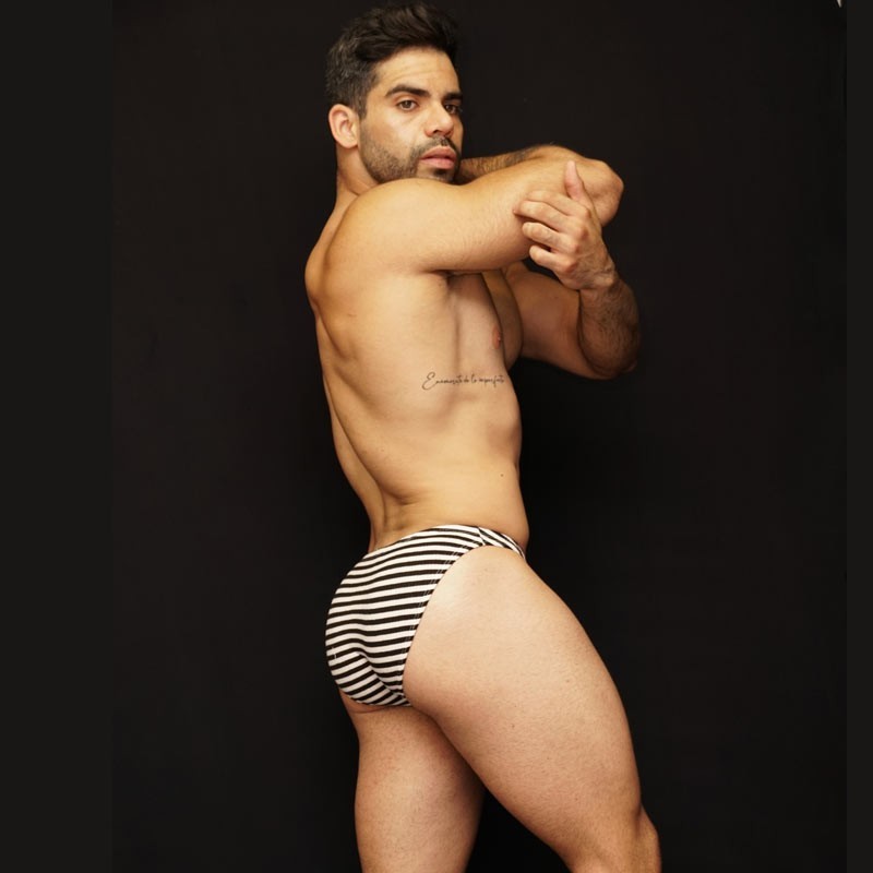 Men's bikini underwear in horizontal black and white stripes made by Arroyman shown on a model from the side.