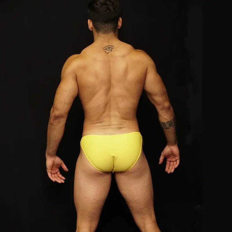 Men's yellow bikini underwear by Arroyman featuring a snug fit and minimal coverage shown from the back on a model.