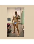 Model wearing blue thong underwear by Arroyman showcasing a snug fit and vibrant color in a locker room setting.