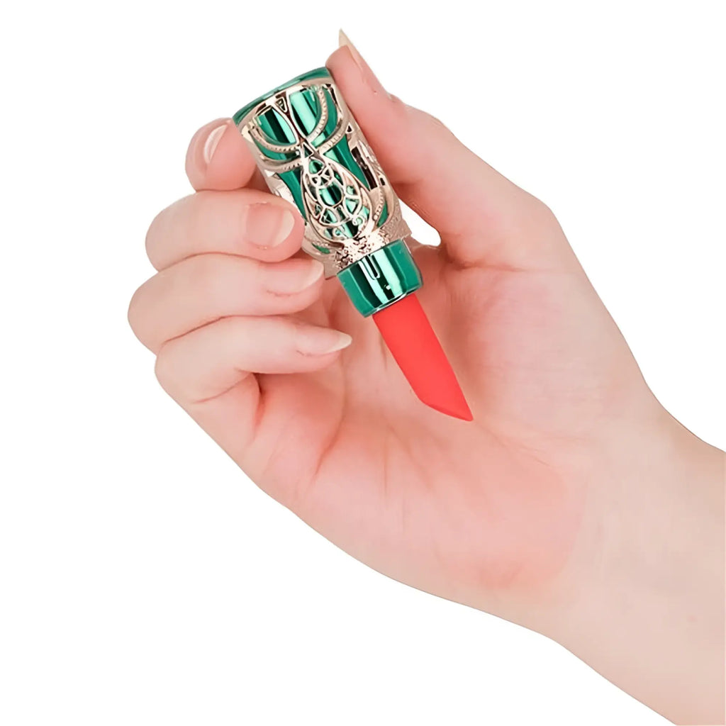 A hand holds a vibrant coral-red BMS emerald kiss 4 in 1 lipstick vibrator with an ornate metallic green and silver cap