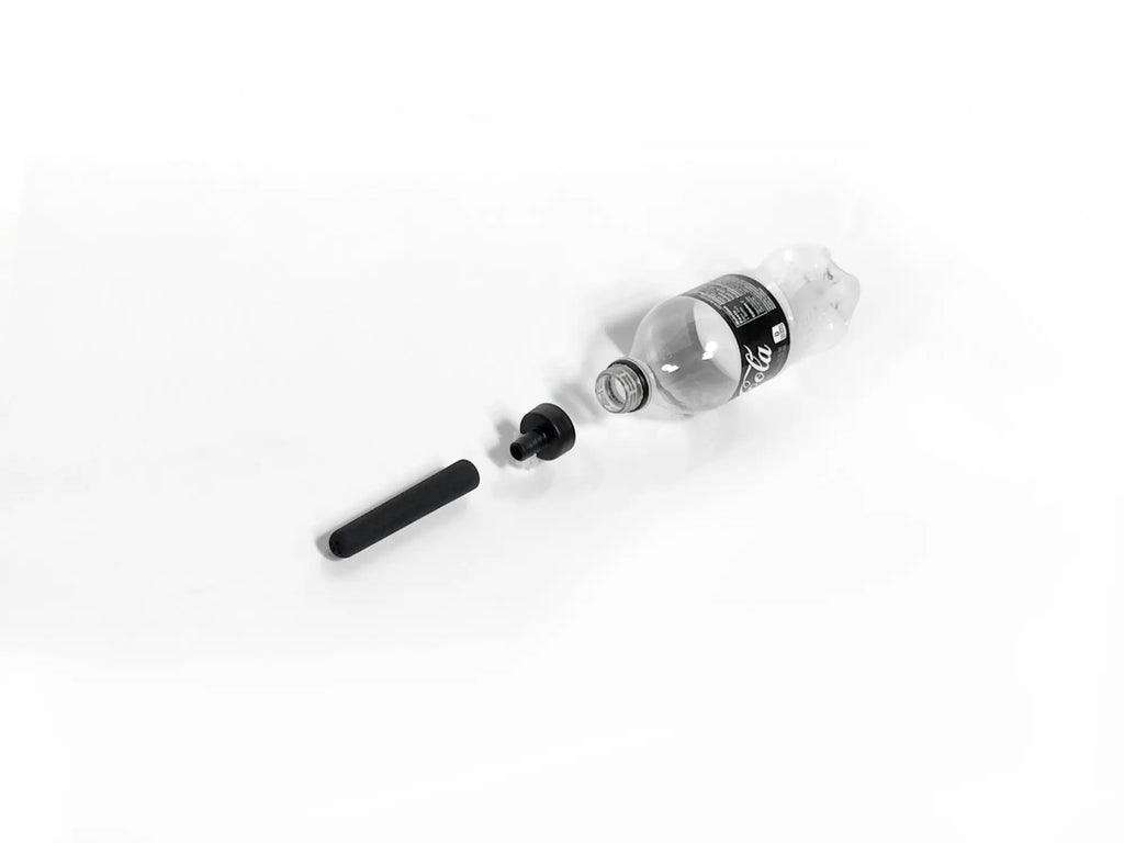 Clear plastic coca-cola bottle with black cap and label disassembled on white surface in boneyard the skwert 5 pc douche kit clamshell
