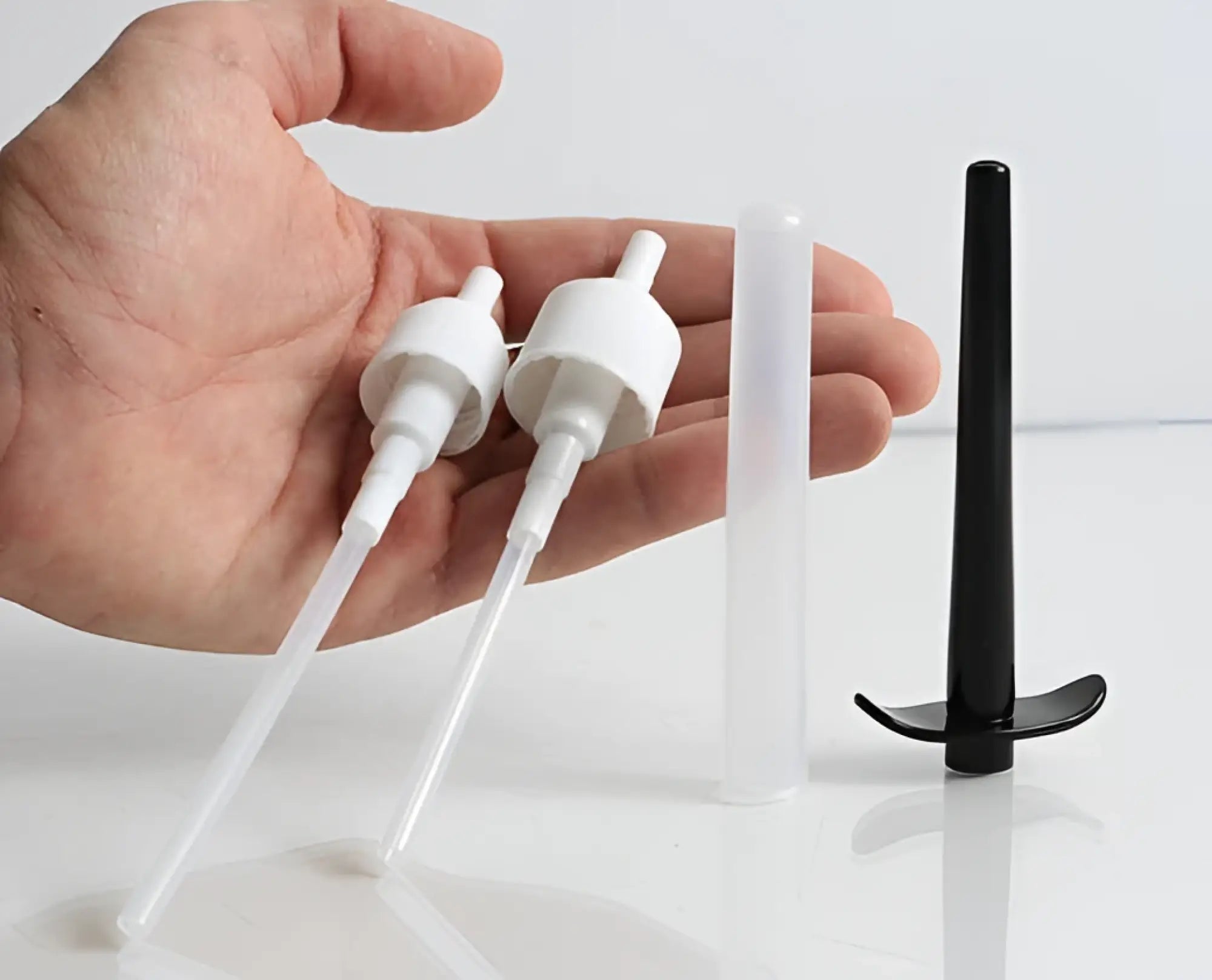 Two white plastic pump dispenser nozzles with clear tubes and one black curved plastic nozzle for boneyard skwert lube injector