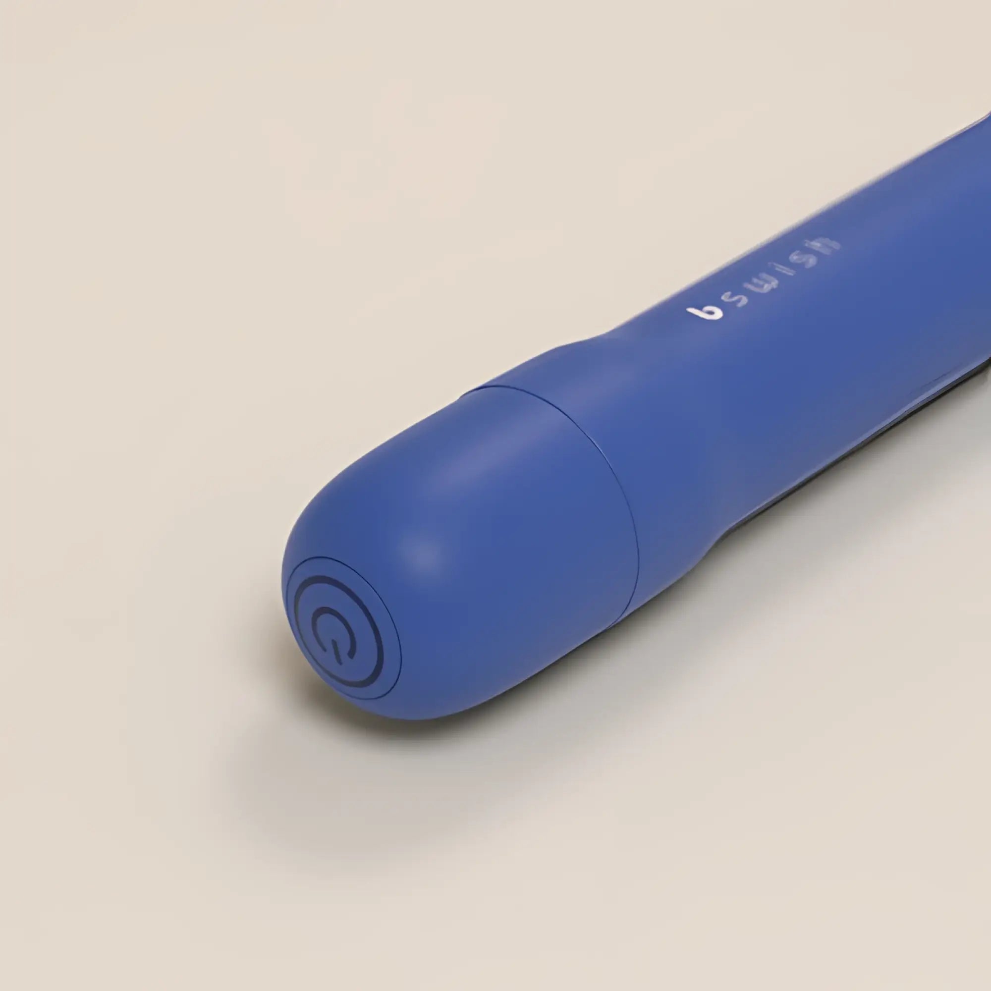 Blue silicone bswish bgee classic denim adult toy with a power button on the rounded end shown from the back side