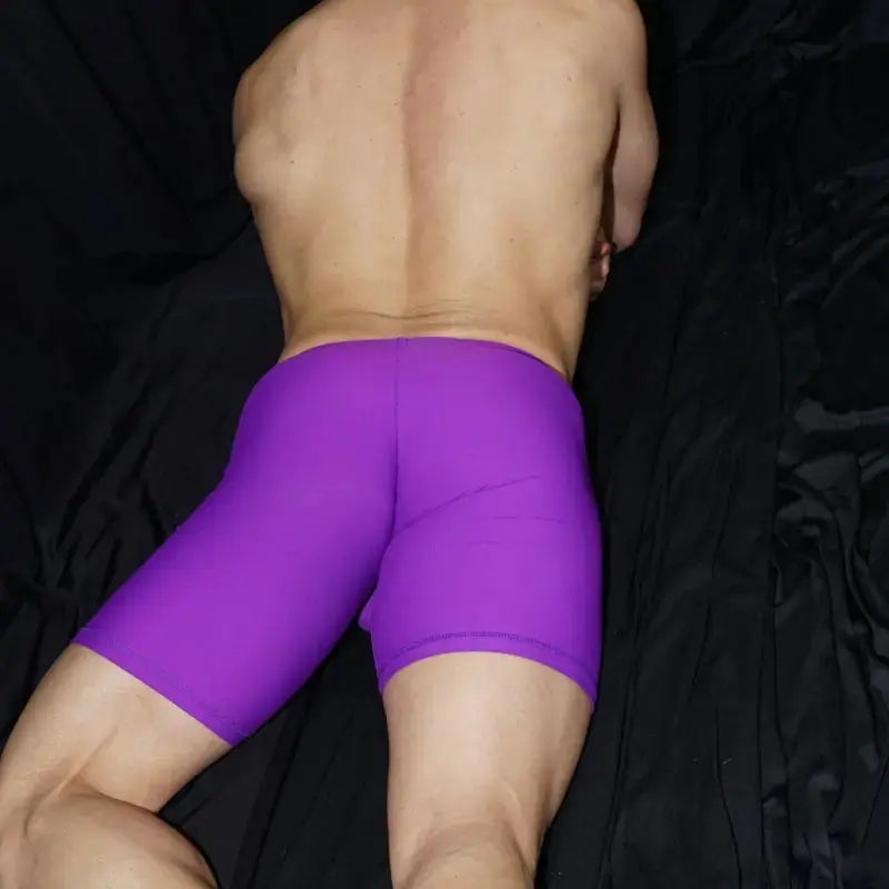 Purple athletic shorts by Arroyman featuring a snug fit and smooth material shown from the back on a model.