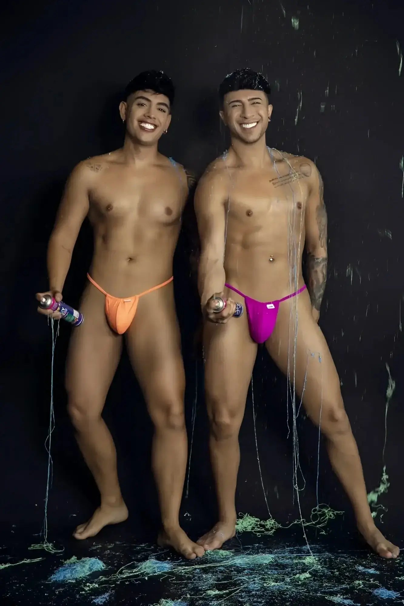 CandyMan 9586 G-String in magenta; lifestyle shot of two men wearing thongs against a black background.