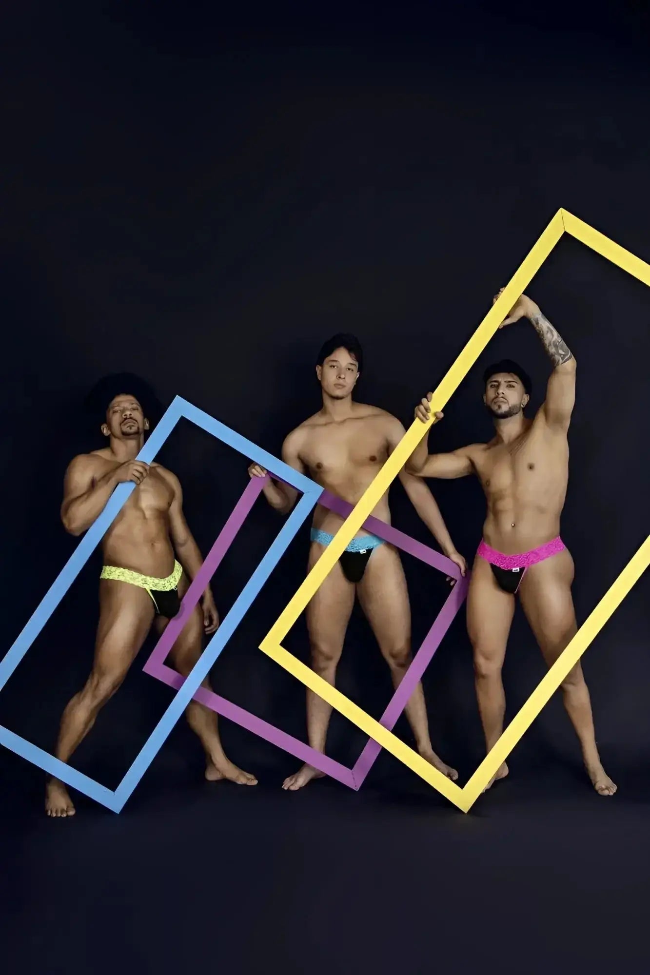 Three men pose with colorful oversized rectangular frames highlighting candyman 99370 lace thongs in hot green
