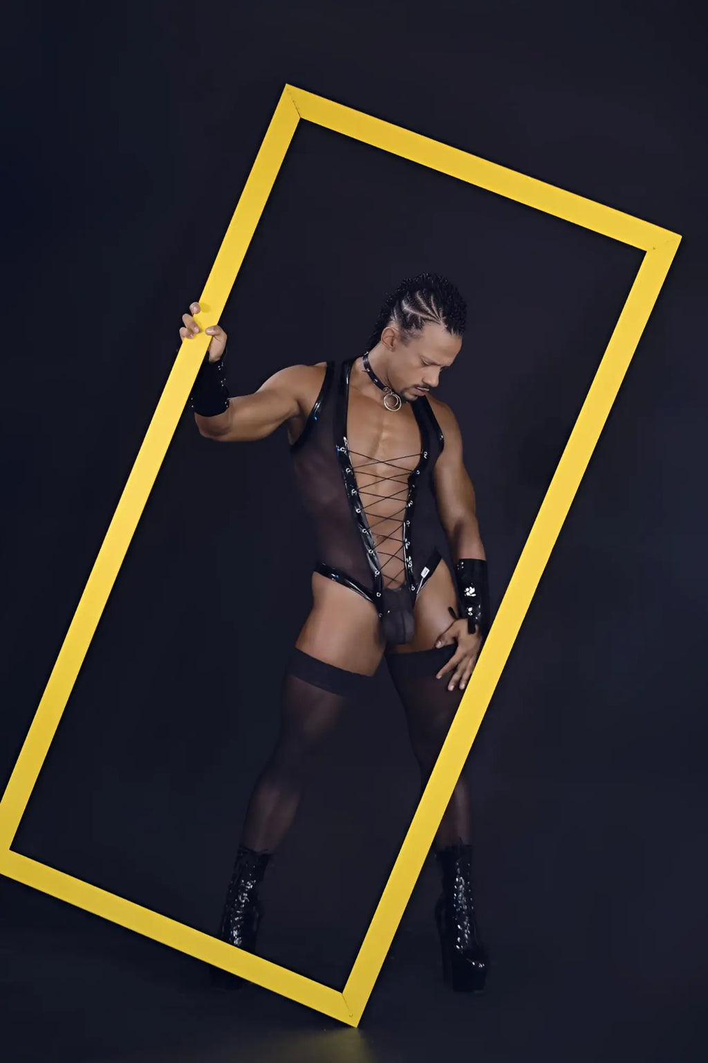 A bold yellow rectangular frame highlighting the black CandyMan 99774 Gladiator bodysuit front side design