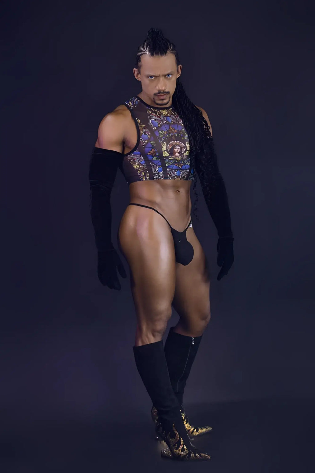 A man wearing a candyMan 99805 stained glass sheer crop top in black with gold and blue patterns over black sleeves