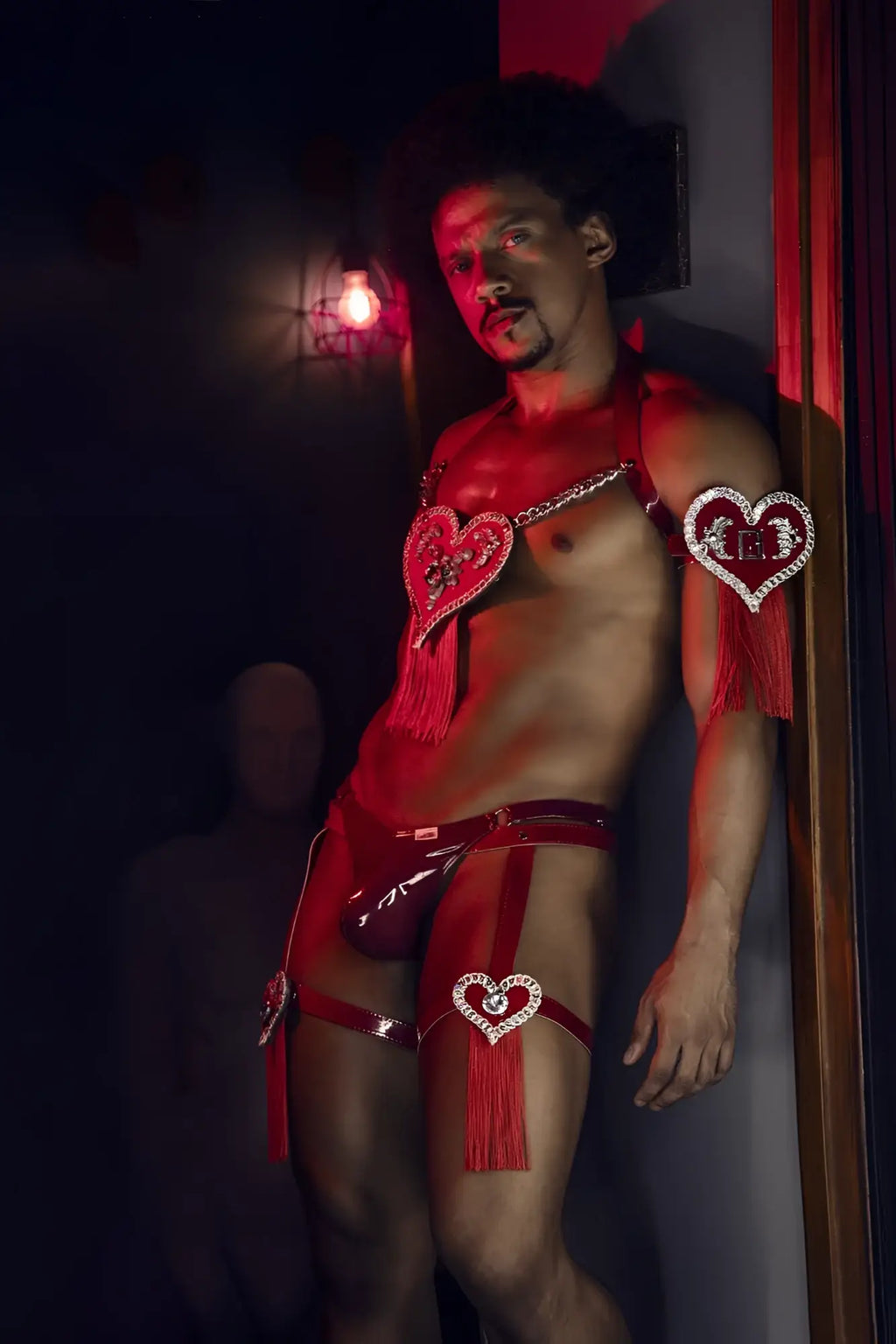 Red heart-shaped rhinestone embellishments with tassels adorn a shiny red latex dom thong candyMan 99819 gloss wine