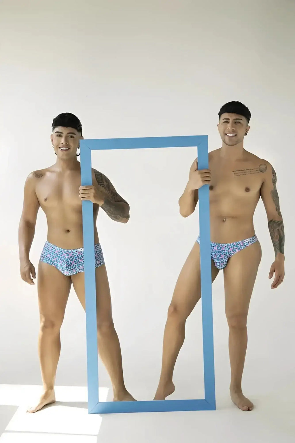 Lifestyle shot of two models wearing CandyMan 99922 printed blue trunks holding a blue frame.