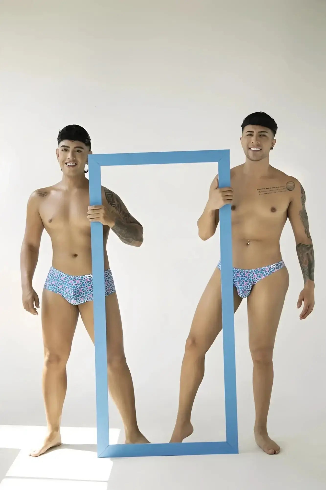 Lifestyle shot of two models wearing CandyMan 99922 printed blue trunks holding a blue frame.