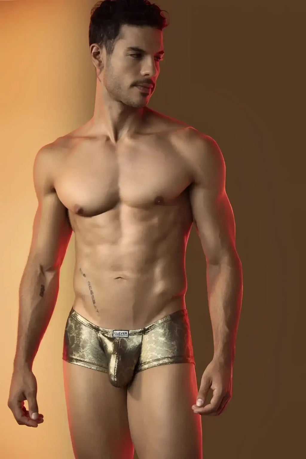 Lifestyle shot of a man wearing gold metallic Clever 26042 Atlas trunks, front view.