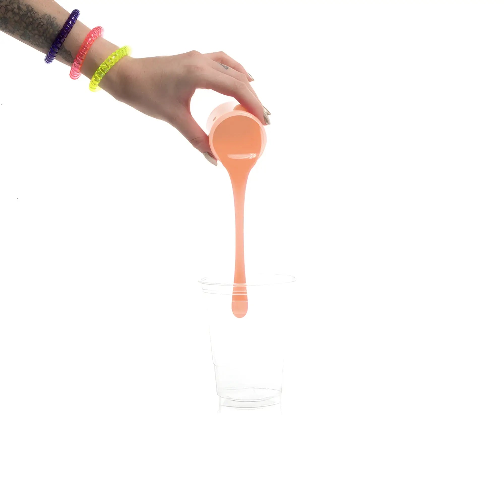 A translucent peach-colored silicone liquid being poured from a measuring cup for clone a willy kit refill flesh