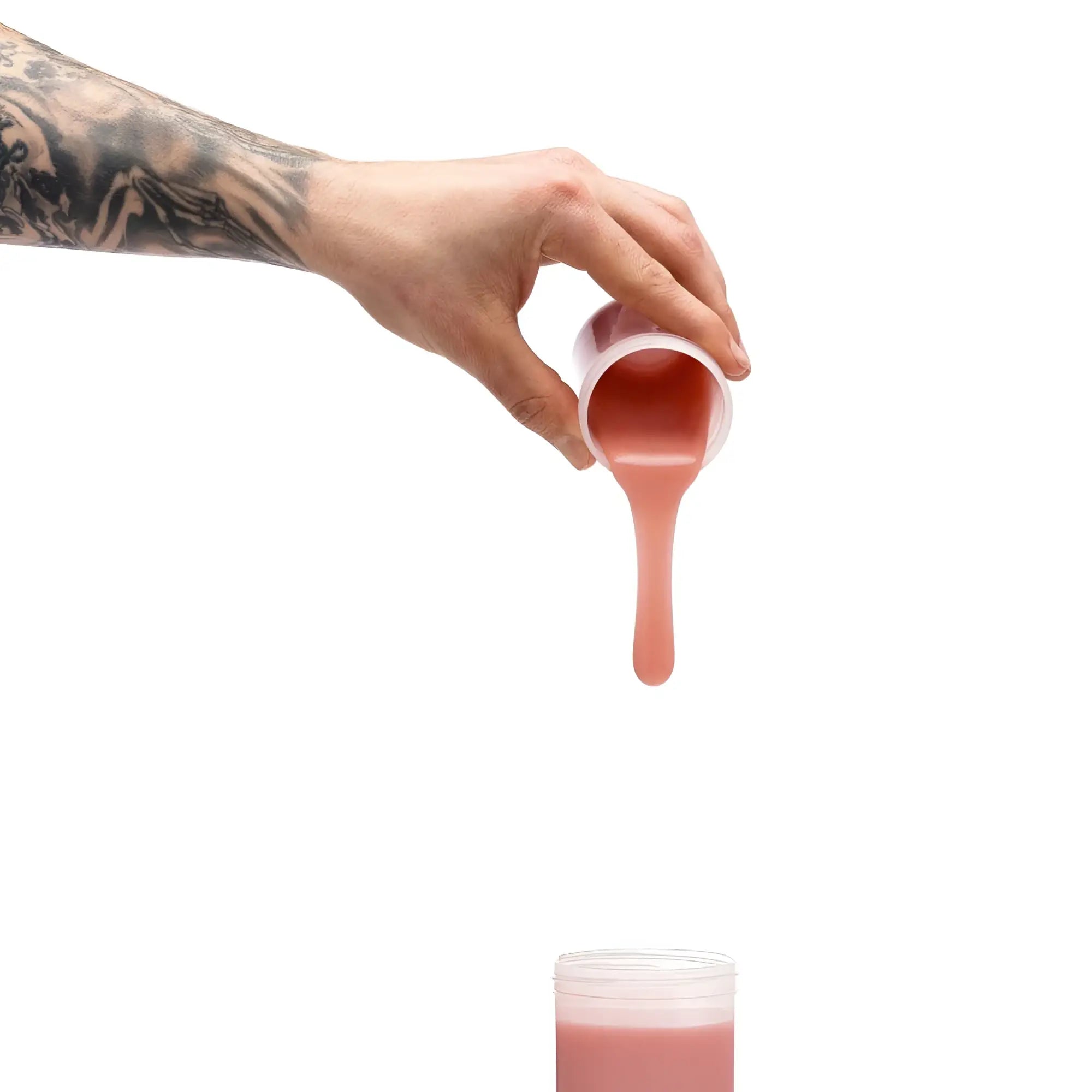 A hand with a detailed black ink tattoo pours pink liquid from a translucent cup using clone a willy silicone refill medium skin tone