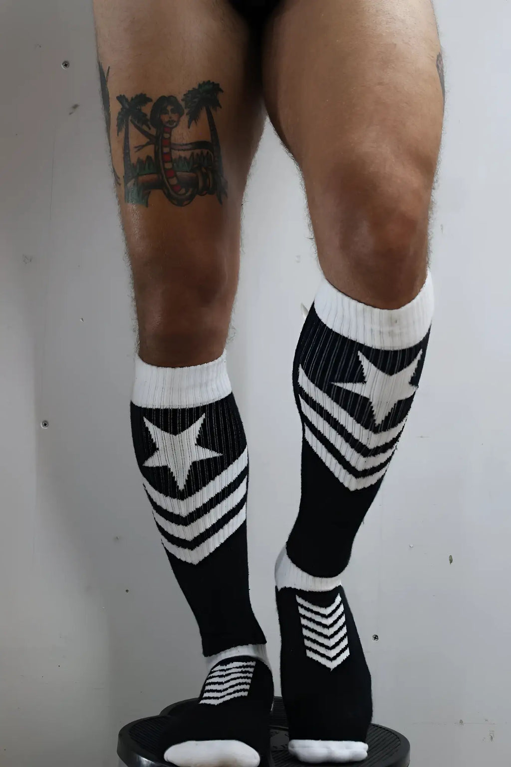 Black and white knee-high cockpit socks with bold star and chevron patterns in cotton blend material