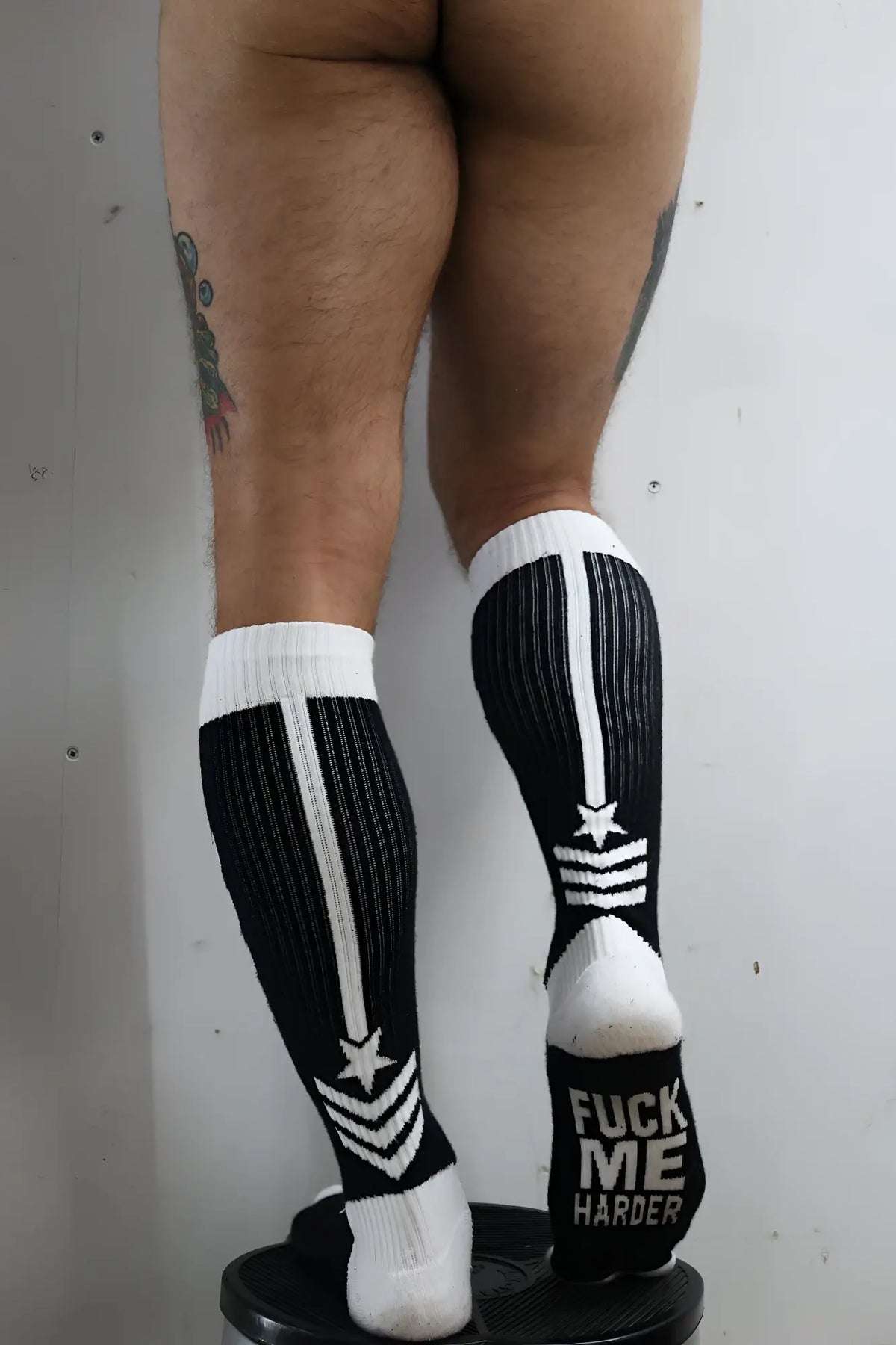 Black and white ribbed knee-high cockpit socks with bold star stripe designs and fuck me harder phrase on the heel back side