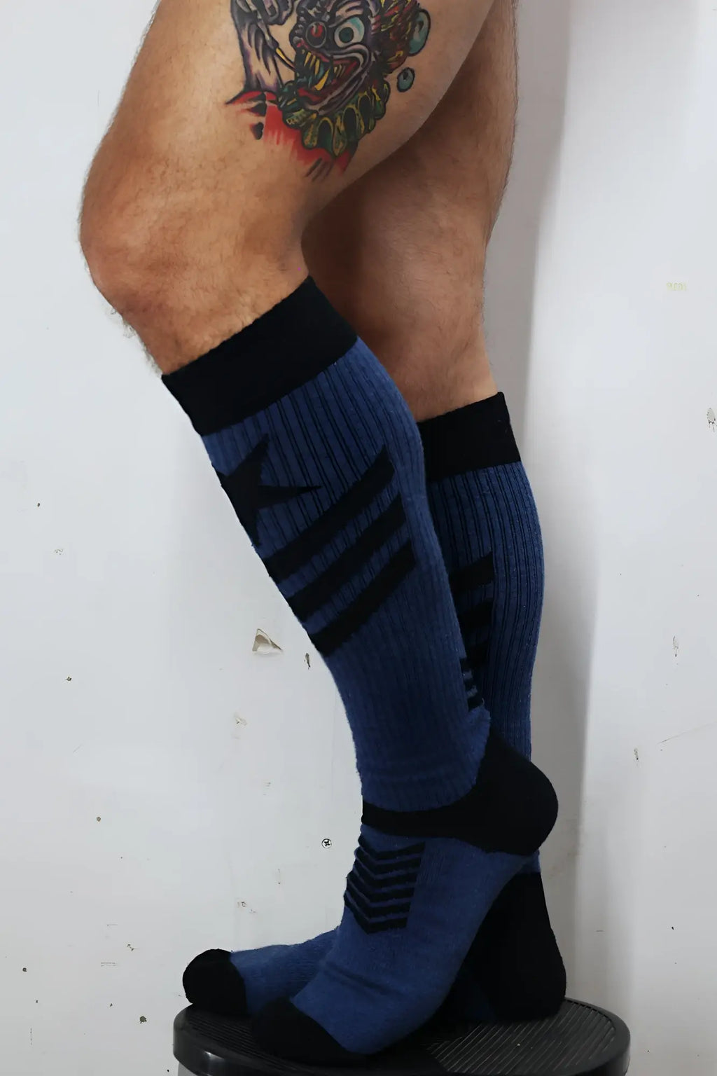 Blue and black athletic knee-high cockpit socks with ribbed texture bold stripes and tactical emblem near the foot