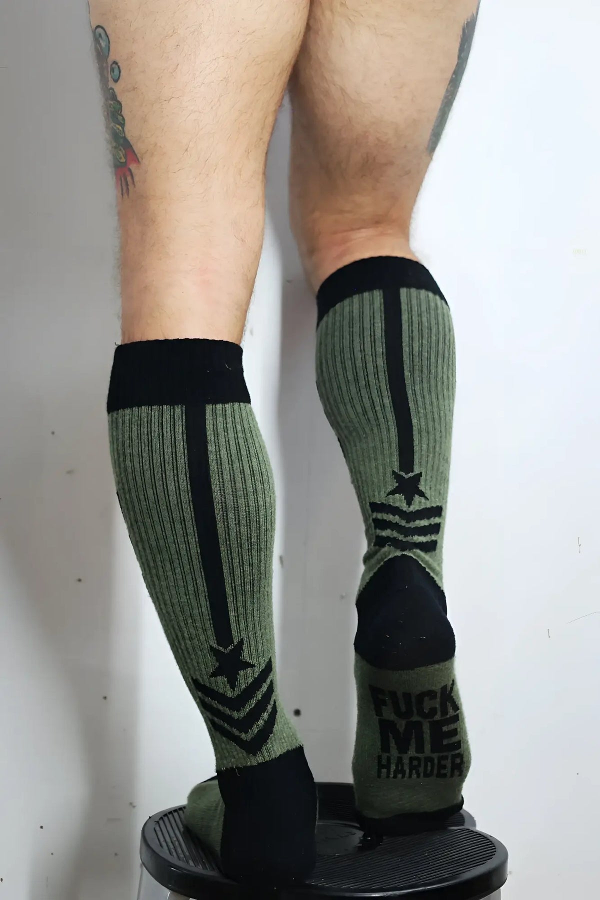 Olive green ribbed knee-high cockpit socks with black accents star and stripe insignia and bold heel text back view