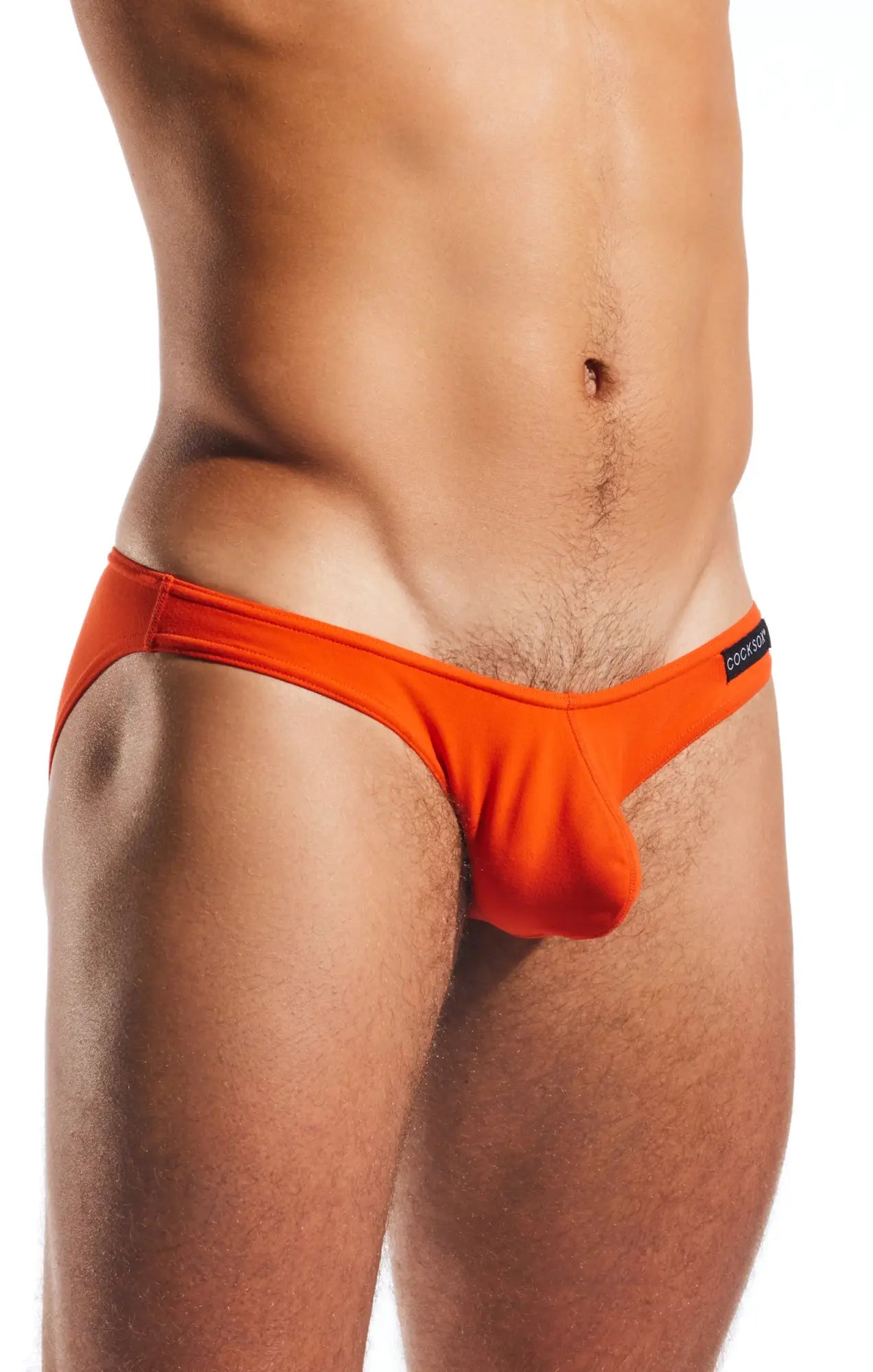 Bright orange Cocksox CX01 brief swim trunks with a sleek modern design and small black brand tag on the waistband