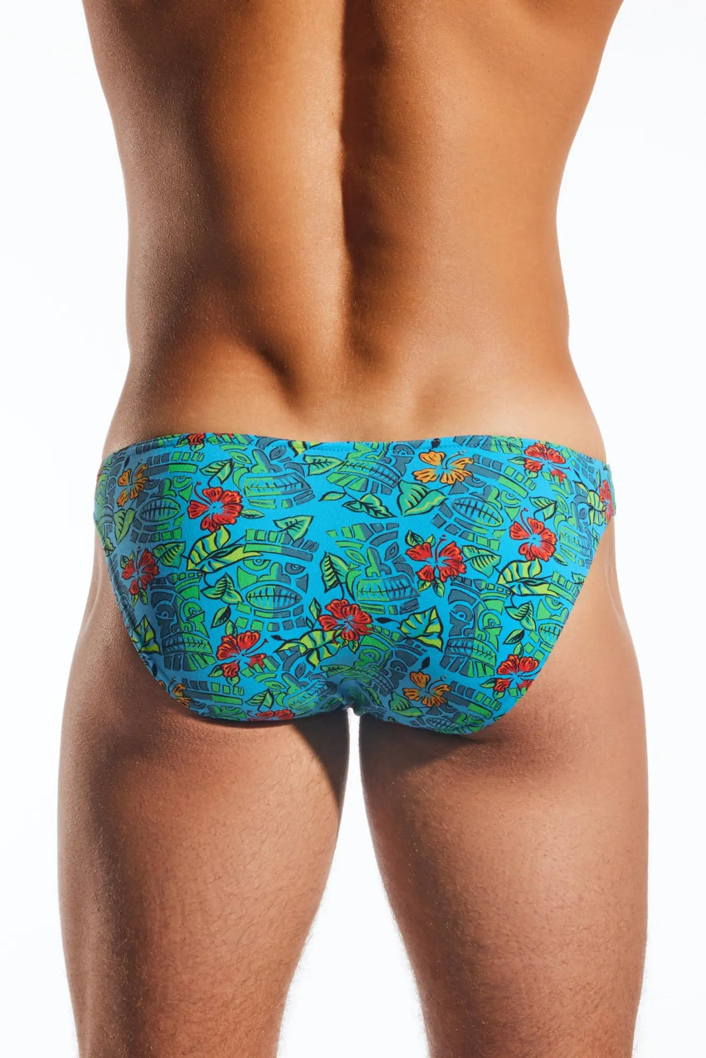 Cocksox cx01 brief vibrant turquoise swim trunks with bold red hibiscus flowers green leaves and stylized ancient masks