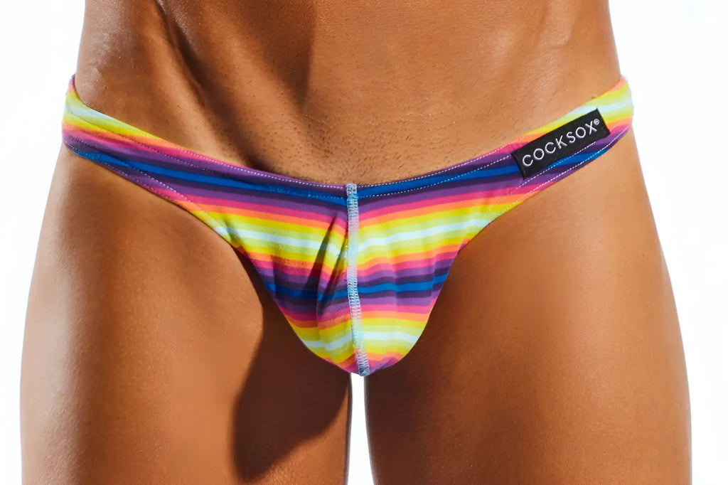 Cocksox CX05 thong in rainbow-striped stretchy fabric with a black brand tag visible on the front side