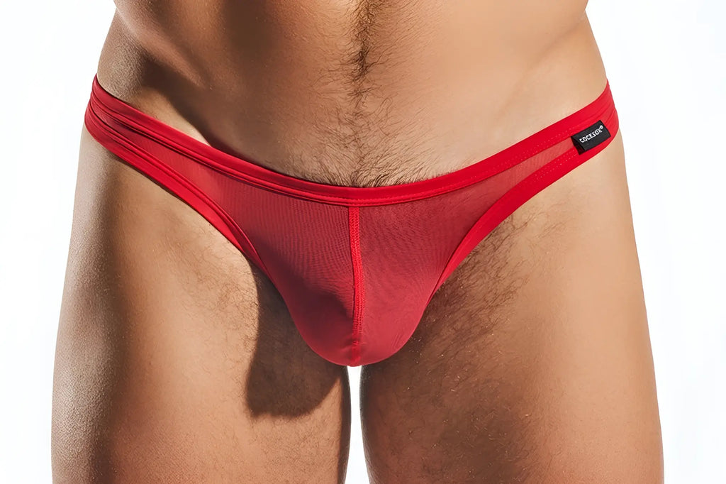 Red mesh thong with solid red waistband and black Cocksox brand tag showing the front side of the CX05ME model