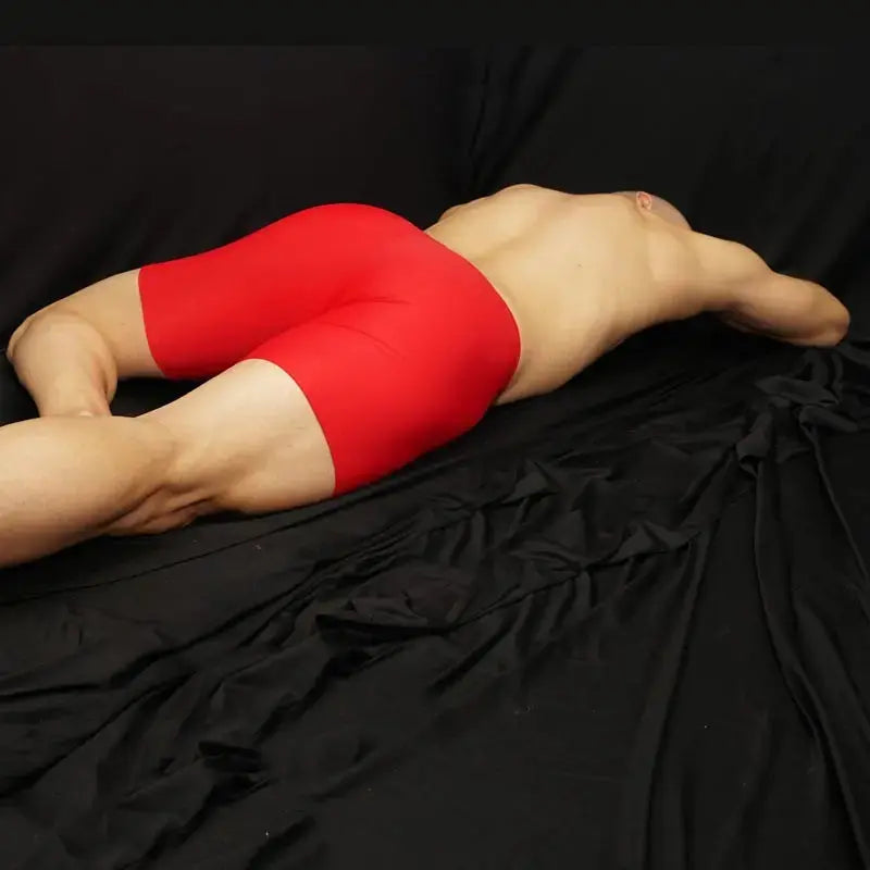 Red compression shorts by Arroyman featuring a snug fit and smooth fabric shown on a model lying on a black surface.