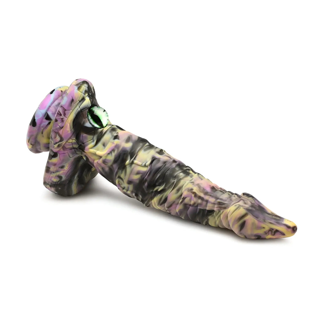 A silicone dildo from creature cocks with a pink yellow and black camouflage pattern and an eye detail on the head