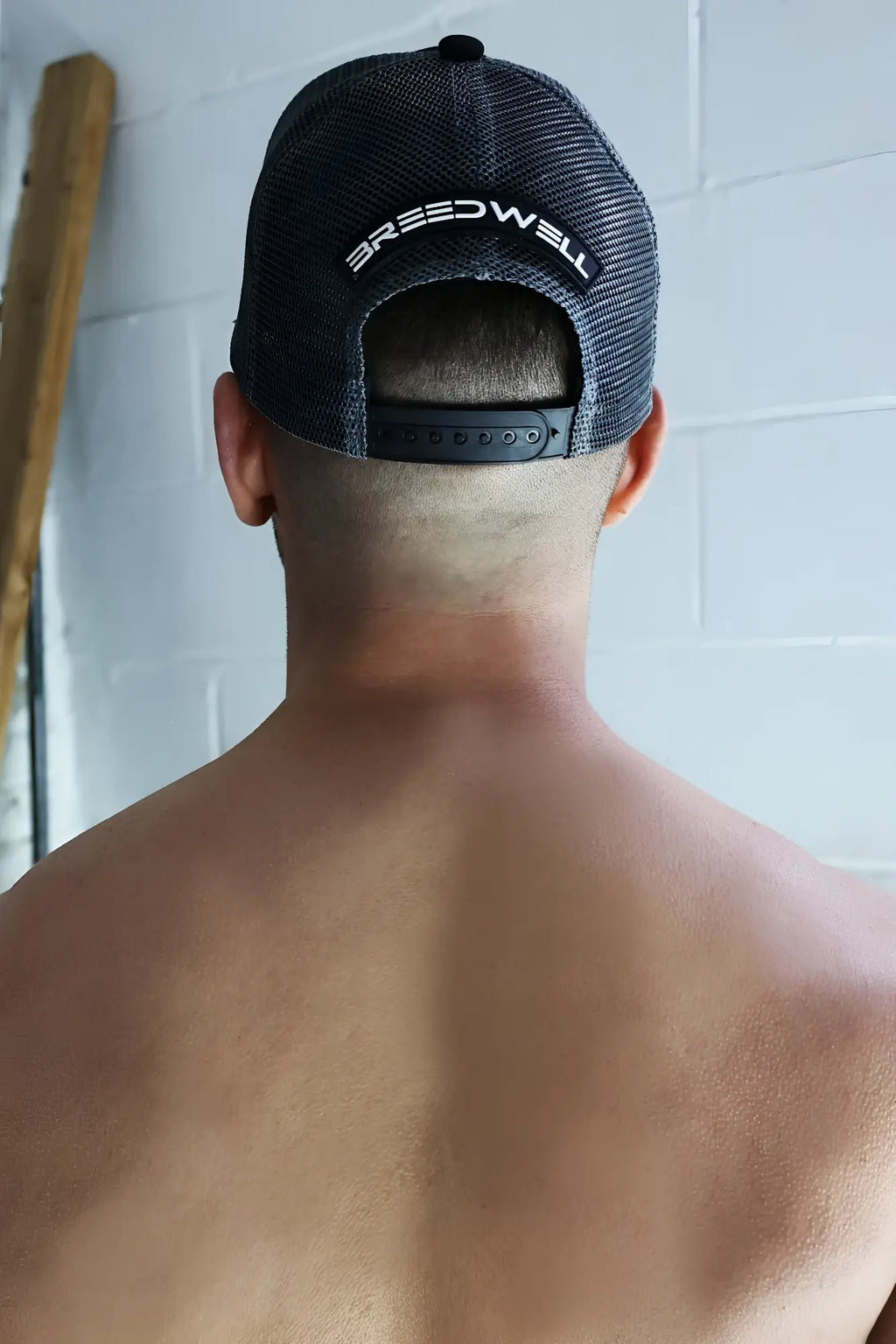 Back side of black mesh dirty trucker hat with white embroidered breedwell logo across the back