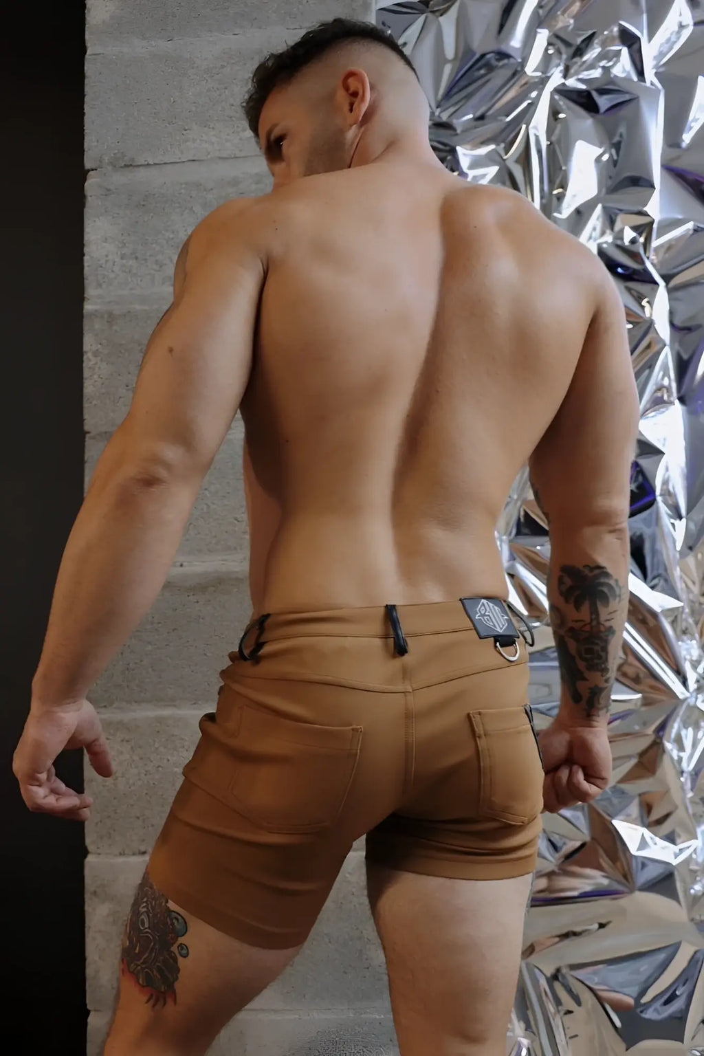 Tan down low cargo shorts with black belt loop and silver-toned metal buckle in dark khaki fabric