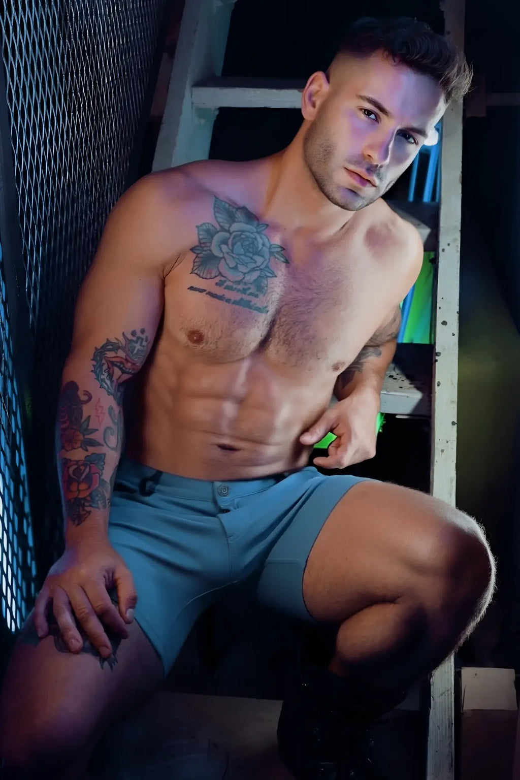A man with tattoos sits on a ladder wearing light blue athletic down low shorts perfect for casual wear
