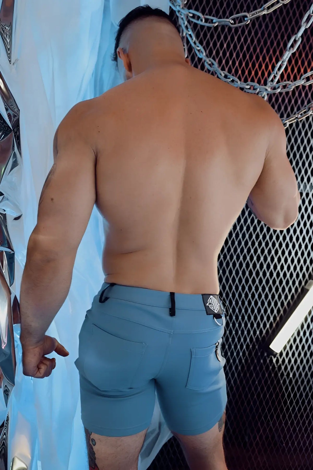 The back side of light blue down low shorts with a black belt loop and small logo patch on the waistband