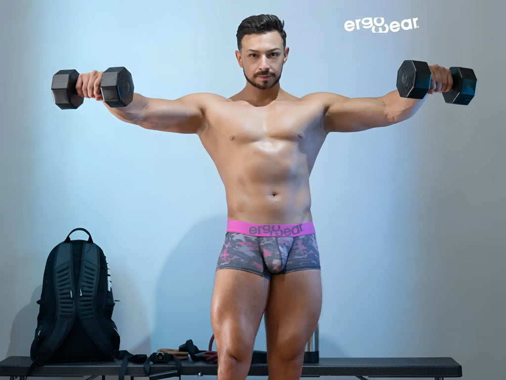 Black hexagonal dumbbells alongside ergowear ew1716 max se camo trunks in pink color for fitness use