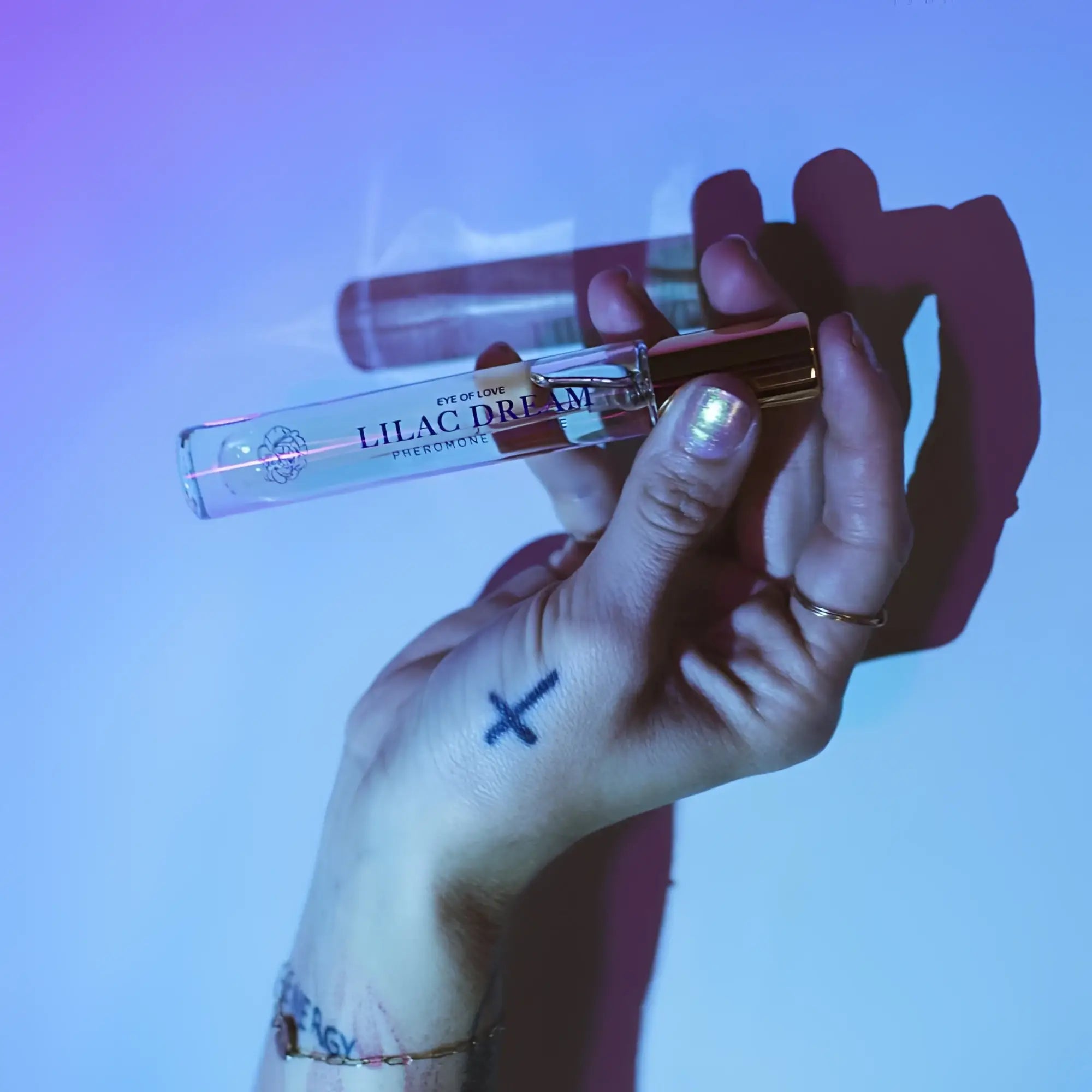 A clear glass perfume vial with gold-toned cap labeled lilac dream by eye of love for attracting him 10ml body spray