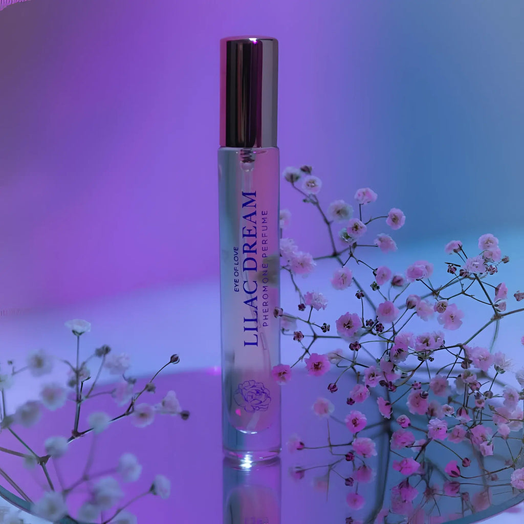A slender transparent glass rollerball perfume bottle with a gold cap and purple lilac dream lettering by eye of love
