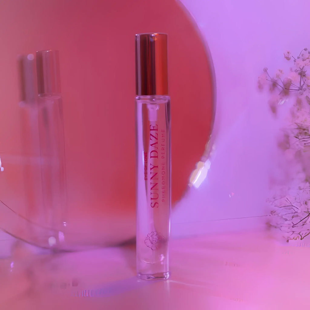 A clear glass roll-on perfume bottle with a metallic gold cap and pink sunny daze text for attracting him