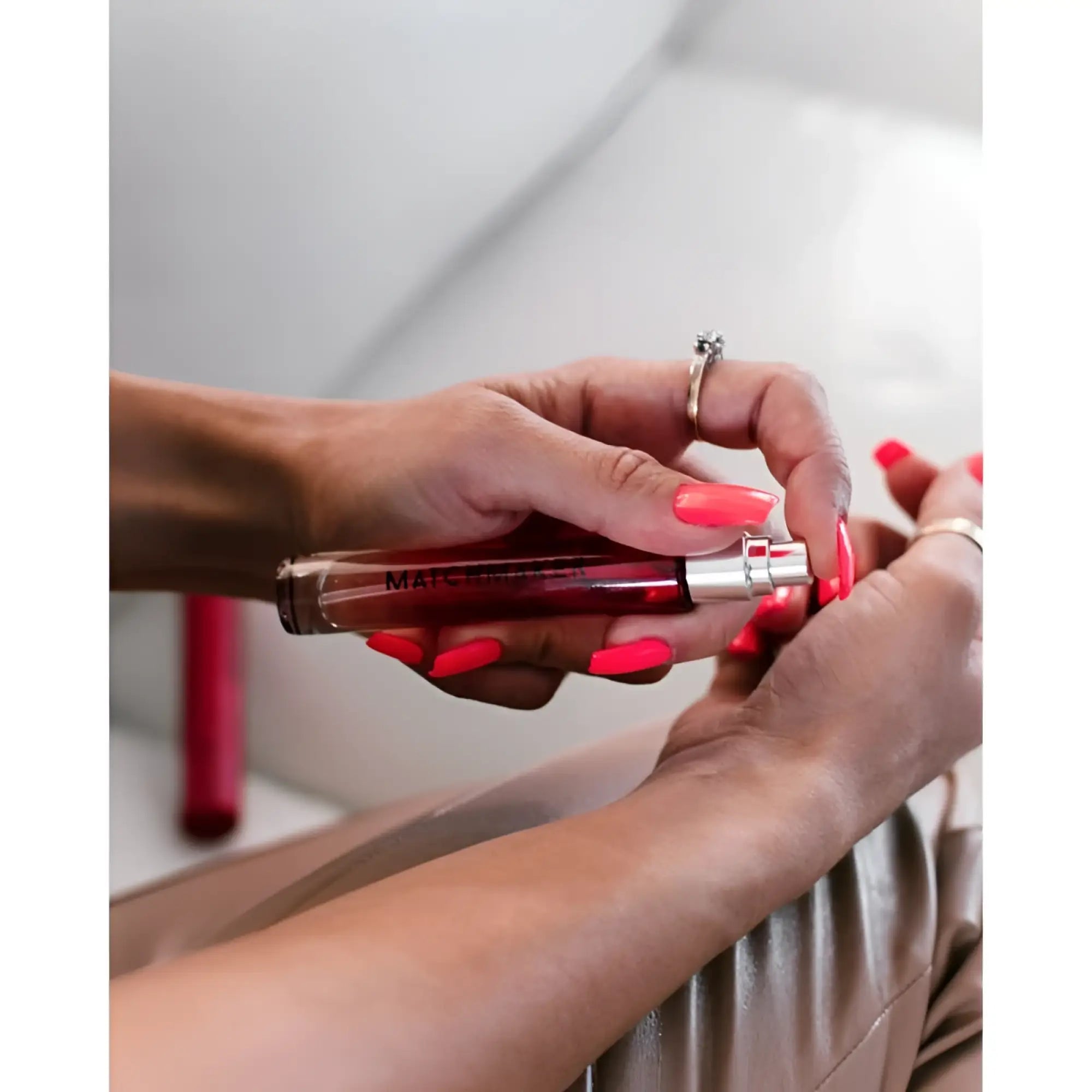 A sleek transparent red mac lipstick tube with silver cap and black branding for eye of love matchmaker pheromone spray