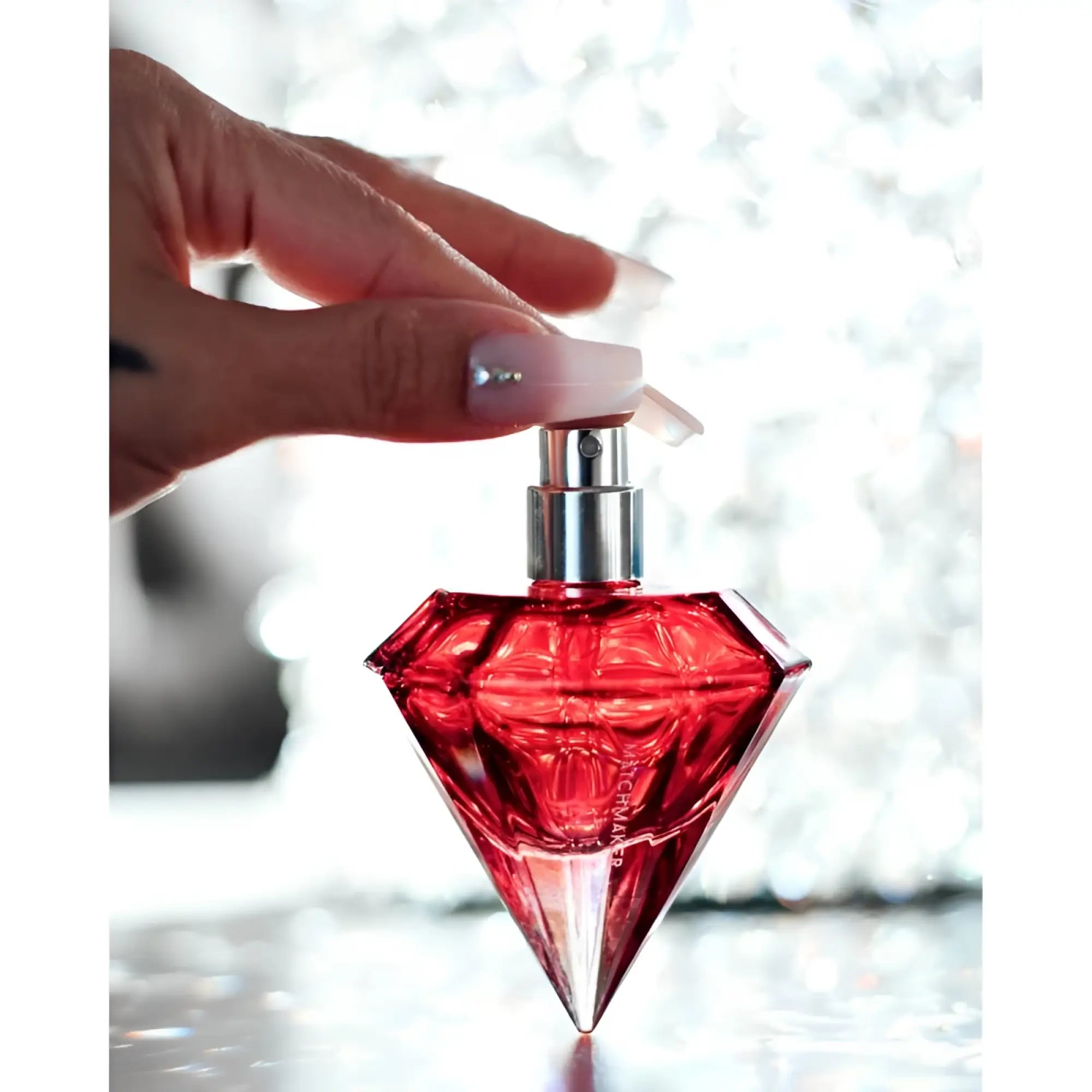 A vibrant red diamond shaped eye of love matchmaker pheromone body spray with a sleek silver nozzle 30ml